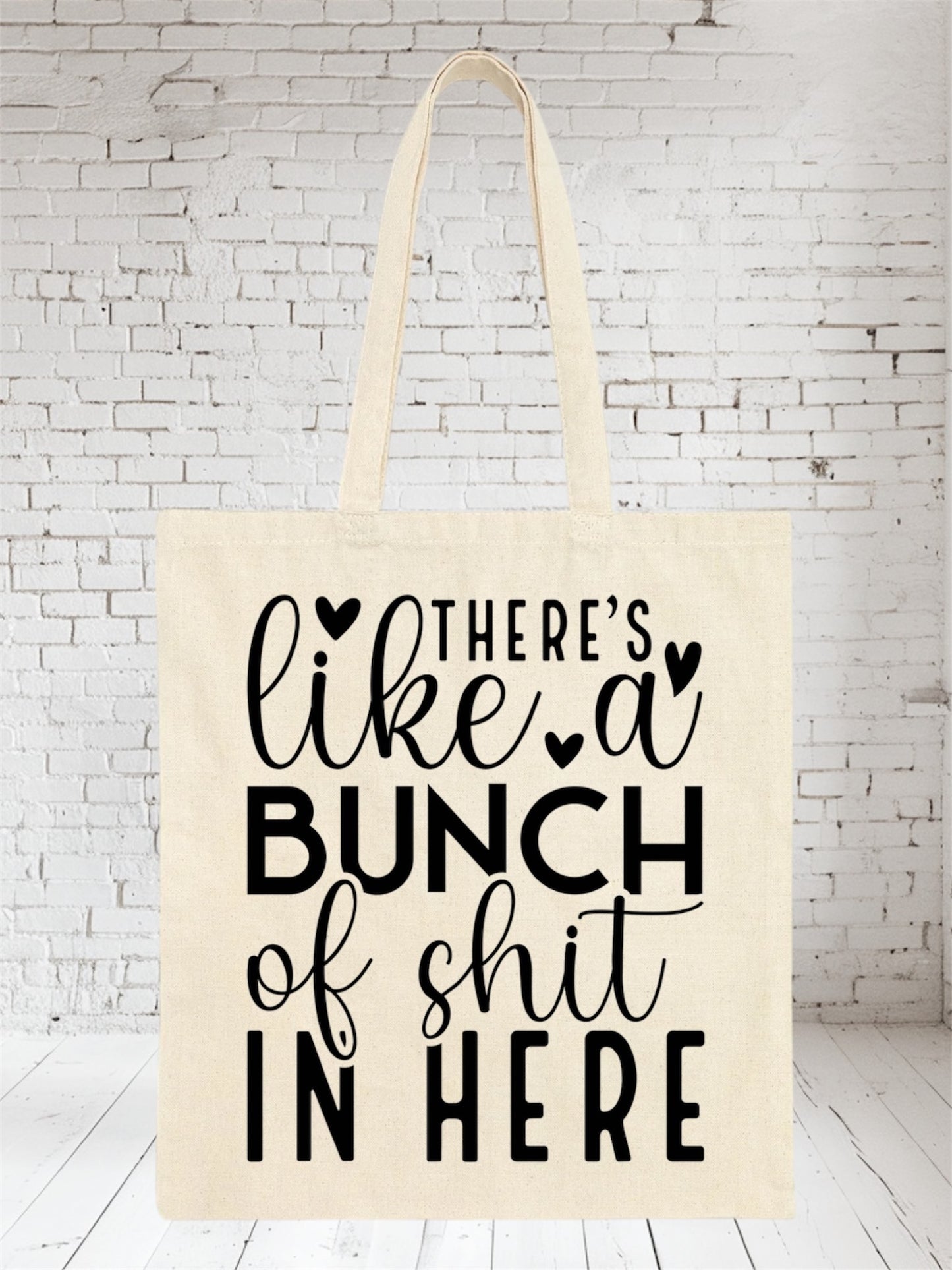 Beige canvas tote bag with black text "There's like a bunch of shit in here"